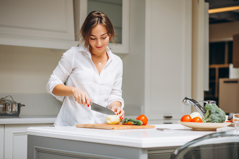 Woman cutting up fiber packed vegetables for a snack, which are beneficial for gut and hormone health.