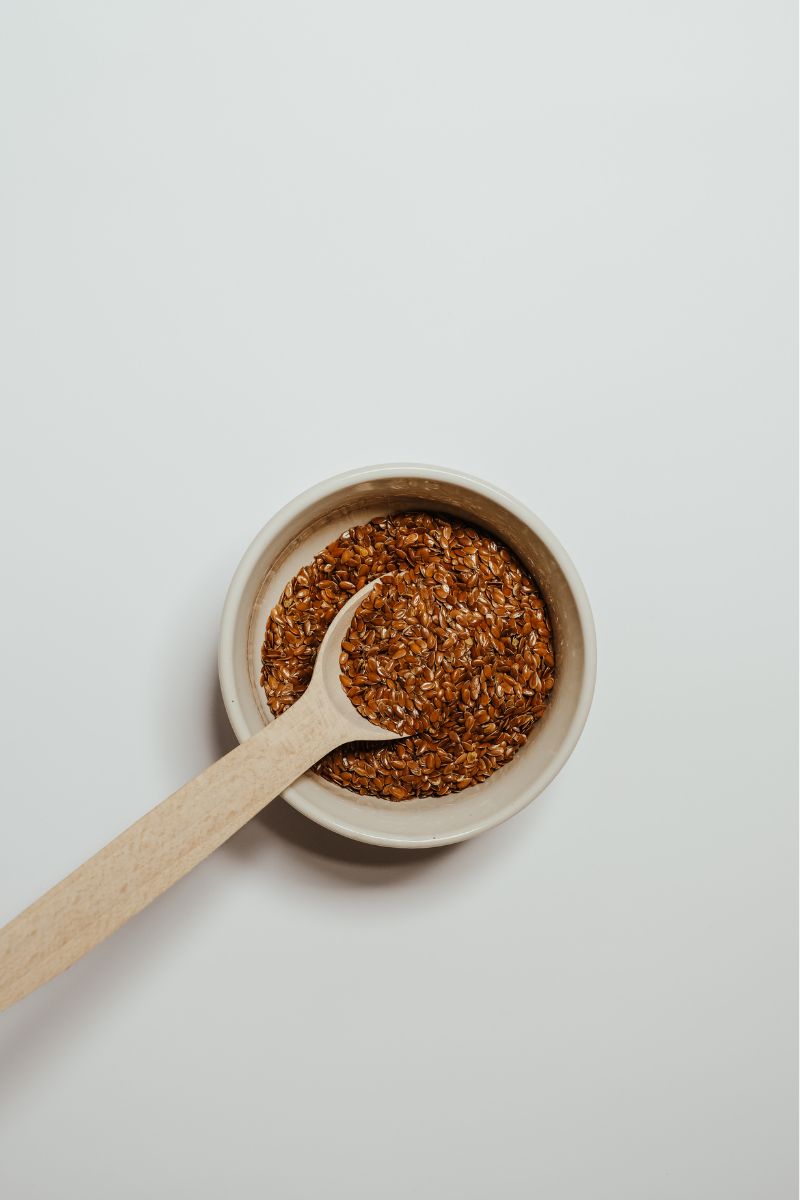 a wooden spoon taking a scoop of flax seeds out of a bowl