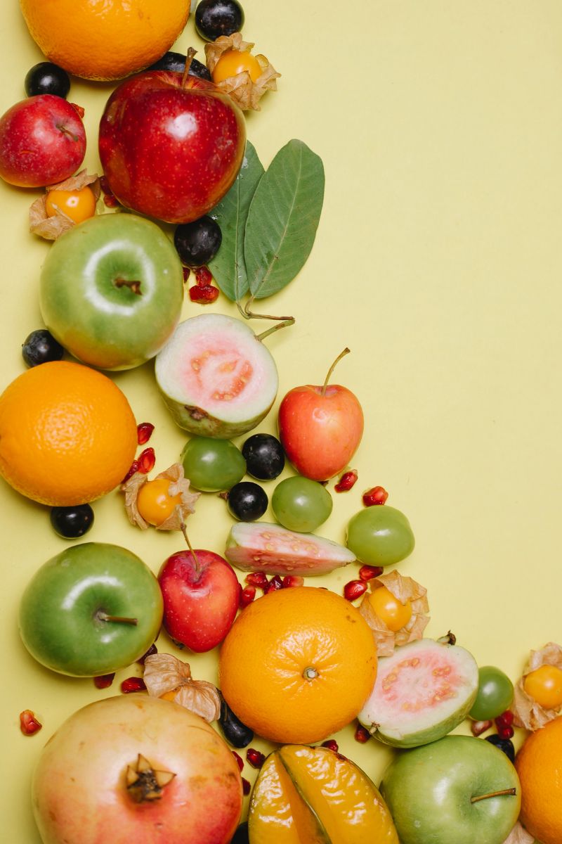 a collection of fruits including apples, oranges, cherries, grapes and berries on a yellow backdrop