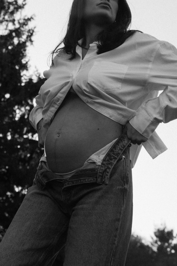 Black-and-white portrait of a pregnant woman outdoors, representing fertility, reproductive health, and the transition into motherhood.