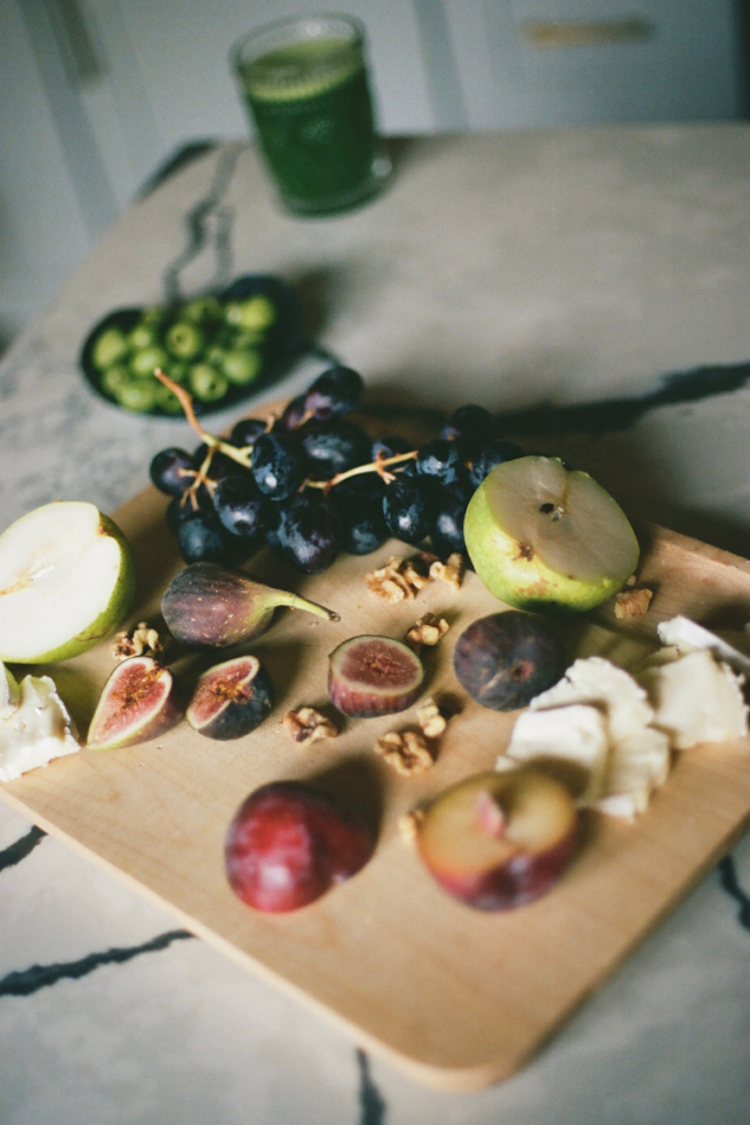 Fresh fruit, walnuts, and nourishing whole foods arranged on a wooden board to support fertility and preconception nutrition.