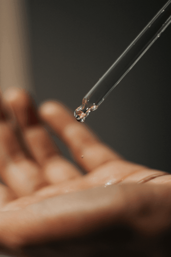 Skincare dropper above a person's hand.