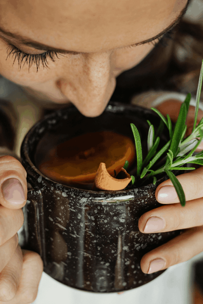 A close up image of a woman holding a mug while sipping her drink out of it. 