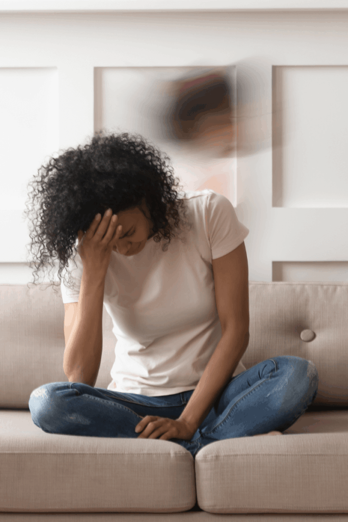 Exhausted woman holding her head in hand while sitting on a couch.