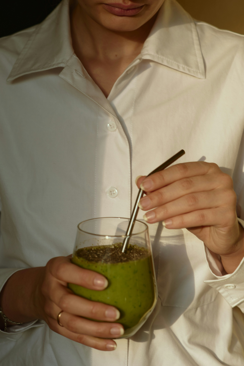 Person holding a green smoothie with chia seeds, representing nutrient-dense foods that support fertility and hormone balance