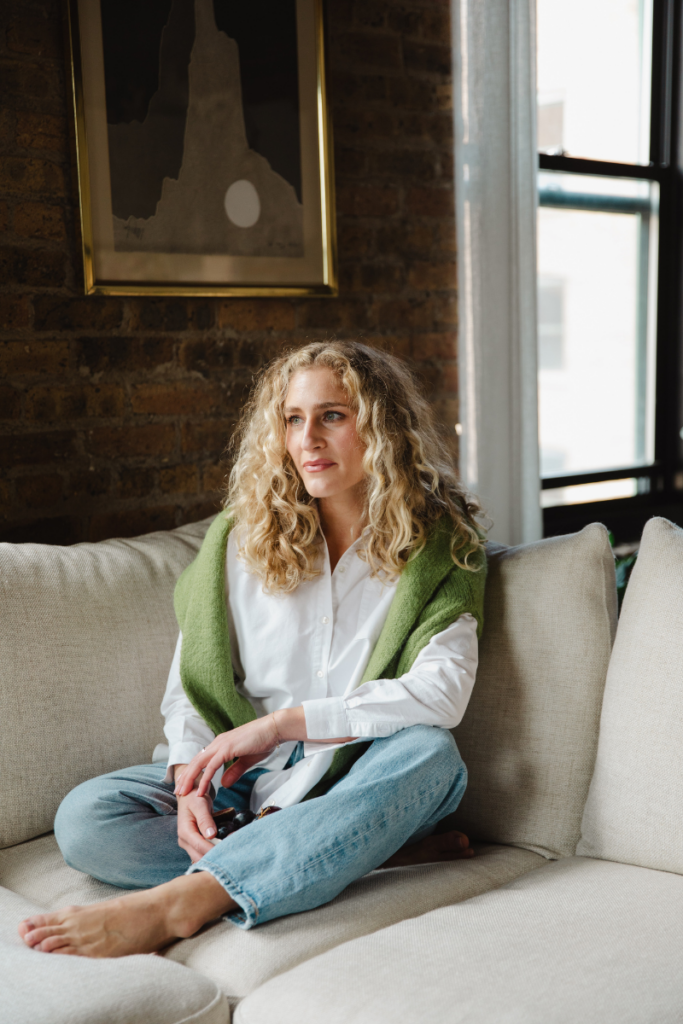 Woman sitting on a couch in a calm home setting, reflecting a holistic approach to fertility and hormone health