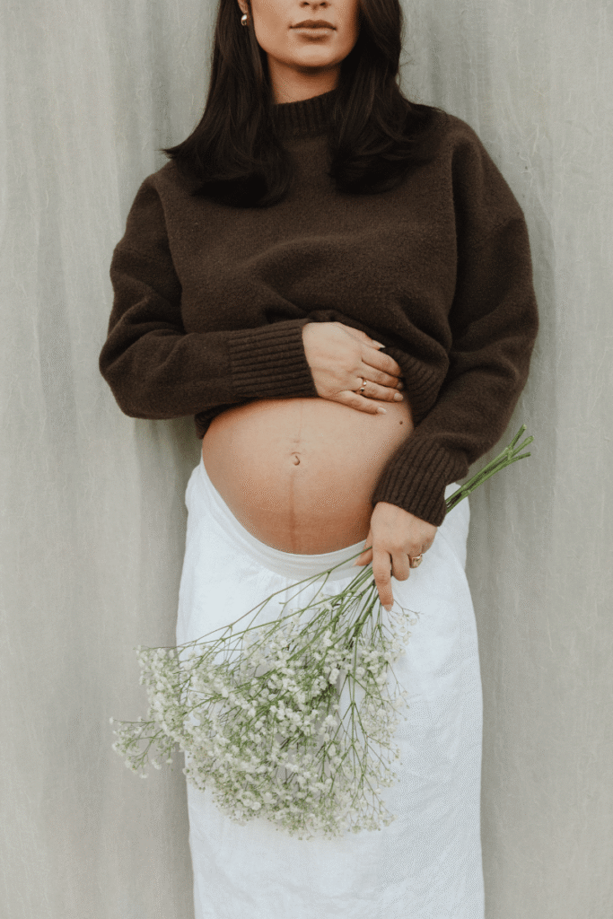Pregnant woman holding flowers, representing trimester zero, preconception health, and preparing the body for pregnancy.